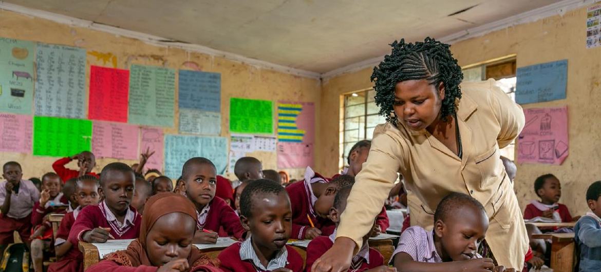 在肯尼亚，老师在课堂上倾身讲解。