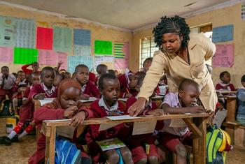 在肯尼亚，老师在课堂上倾身讲解。