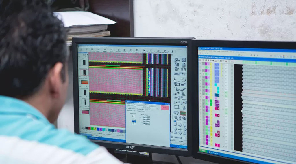 Una persona visualiza un software de análisis de datos en dos monitores de ordenador en un espacio de trabajo.