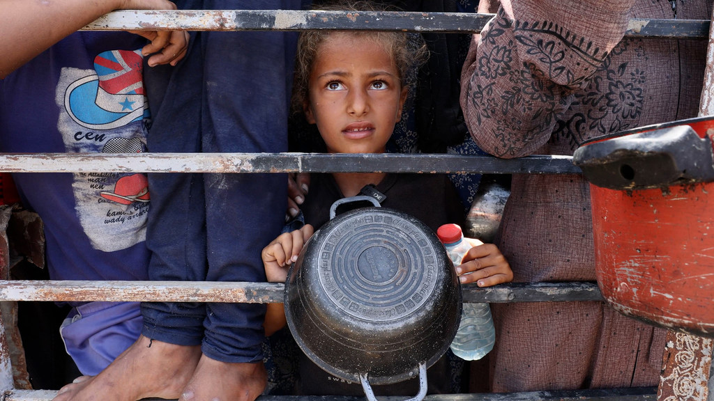 Una niña de Gaza espera para llenar su cuenco de lentejas.
