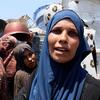 Um Mohammed, une femme qui a fui le quartier de Shujaiya à Gaza, attend avec d'autres femmes déplacées une aide alimentaire.
