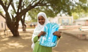 Tawasol, Msichana mkimbizi kutoka Khartoum, ambaye ni mwanafunzi katika shule ya wasichana ya Arabee Aradawiya huko Damazine, Jimbo la Blue Nile akishikilia begi lake huku akitabasamu.