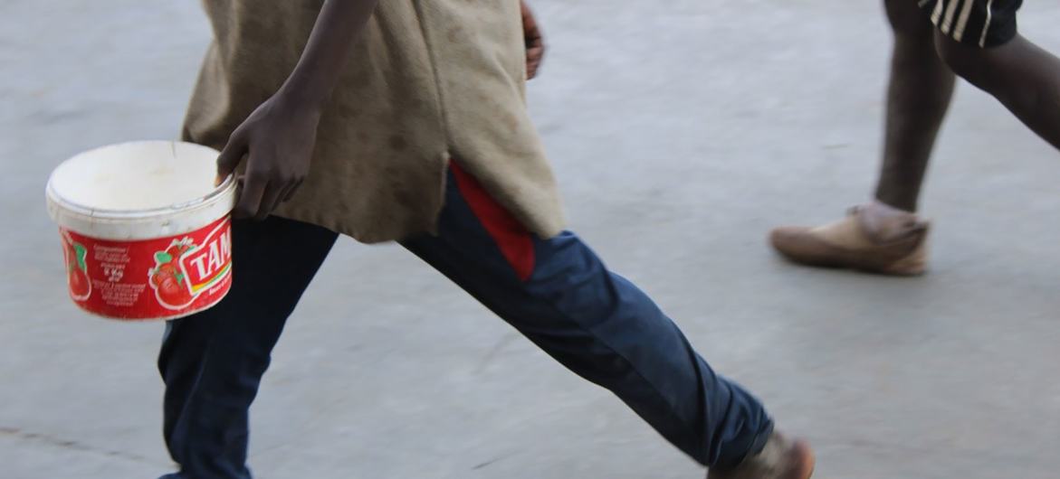 Pieds nus, sébile en main, un garçon mendie pour nourrir son maître au Sénégal.