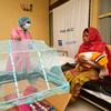 बांग्लादेश के एक प्राथमिक स्वास्थ्य केन्द्र में एक दाई, एक नई माँ को शिशुओं की मच्छरदानी का उपयोग करना सिखा रही है.