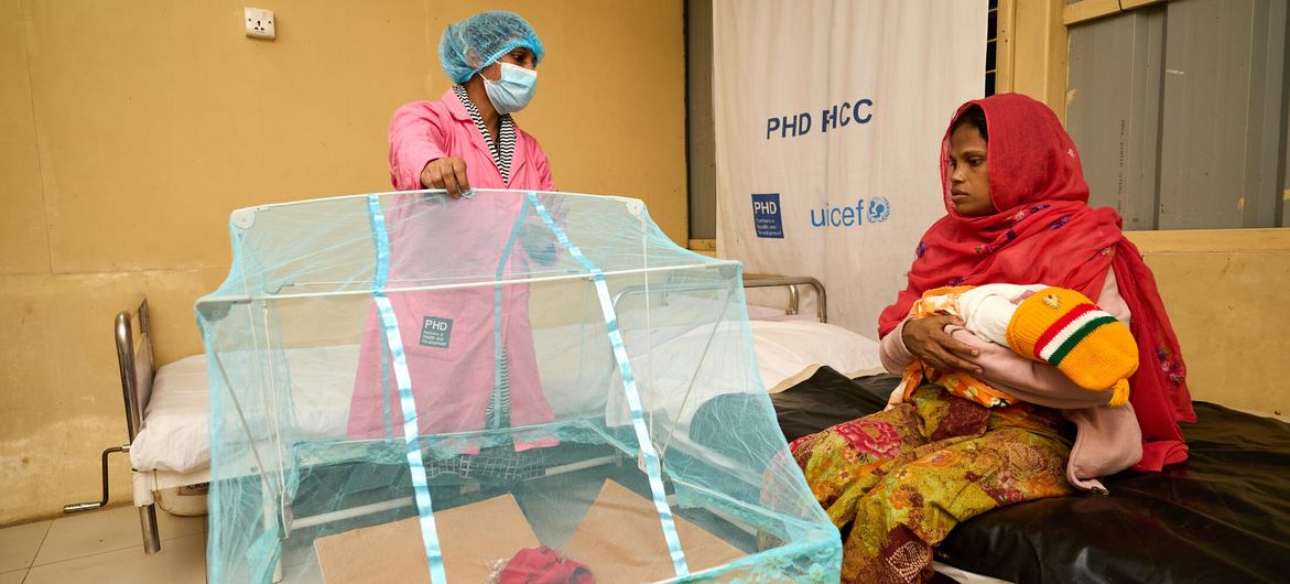 A midwife demonstrates the use of a mosquito net, designed for infants, to a new mother at a primary health centre in Bangladesh. 