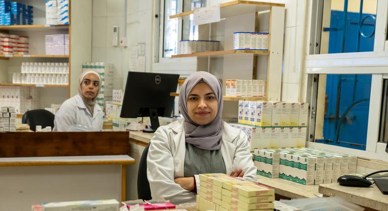 Wafamasia wawili wa kike waliovaa koti jeupe na hijabu wamesimama katika duka la dawa katika kituo cha afya cha UNRWA katika Kambi ya Wihdat, Jordan.