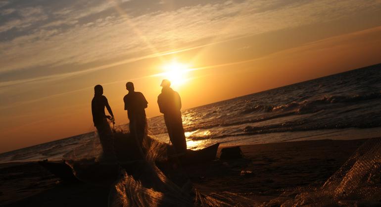 Silhouettes za wavuvi wa Kipalestina wakikusanya nyavu zao kwenye ufuo wa Gaza wakati wa machweo.