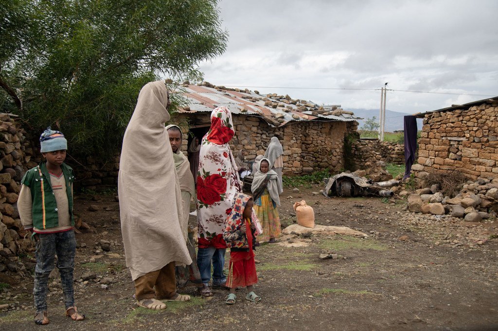 Niños y adultos de pie frente a una casa familiar, con restos del conflicto recogidos en su patio delantero en Gijet, Tigray, Etiopía, el 20 de julio de 2021.