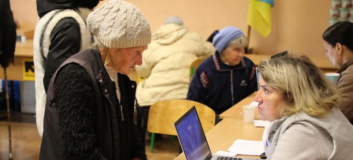 Пожилая женщина регистрируется в транзитном центре в Харькове.