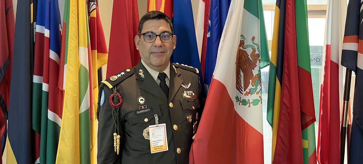 El general de brigada Ramón Guardado Sánchez, con su uniforme militar, se encuentra entre las banderas de las naciones en la Sede de la ONU en Nueva York.