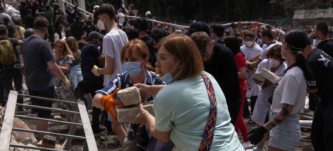 Des Ukrainiens ramassent des gravats et des débris après une frappe de missile à Kyiv.