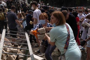  Люди расчищают завалы на месте ракетного удара по Киеву 8 июля 2024 года.