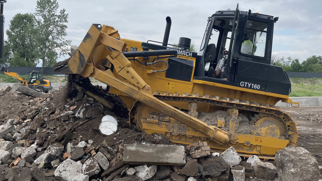 Желтый бульдозер Demag GTY160 разгребает завалы во время послевоенной восстановительной операции на Украине.