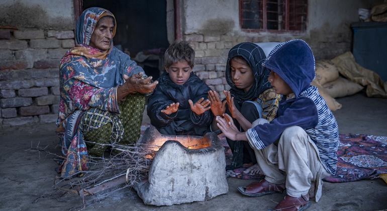 Хава Биби и ее внуки греются возле печки перед своим домом в Пакистане.  