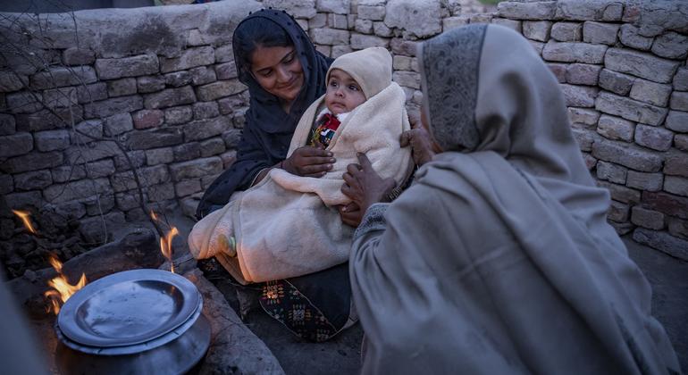 Мать согревает своего восьмимесячного сына возле печи во время холодов в Пакистане.