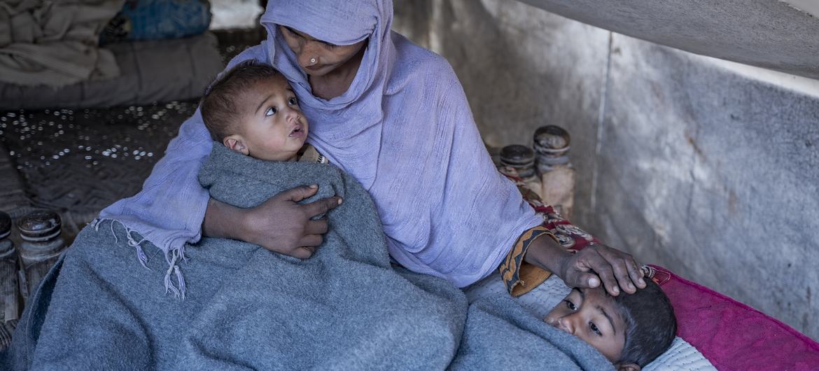 पाकिस्तान के एक बाढ़ प्रभावित गाँव में, यूनीसेफ़ से मिले टैंट में, एक महिला लक्खी बीबी, अपने बच्चों को गर्माहट का माहौल देने की कोशिश करते हुए. देश में वर्ष 2022 में, लाखों बच्चे भी बुरी तरह प्रभावित हुए हैं.