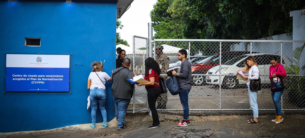 Imigrantes venezuelanos na fila superior recebem visto de regularização concedido na República Dominicana.