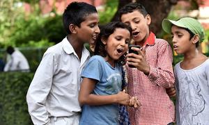 Children at St. Columba’s School, Delhi, India, use a mobile phone