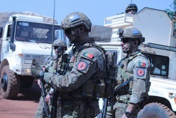 Soldados portugueses de manutenção da paz, trajando equipamento militar, em frente a um veículo da ONU .