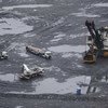 Vista aérea de uma operação de mineração no Brasil, mostrando uma grande escavadeira e vários caminhões em um terreno lamacento e úmido.