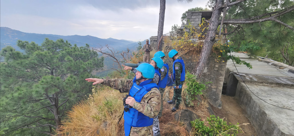 El contralmirante argentino Guillermo Ríos, jefe de misión de la UNMOGIP, señala una vista desde un puesto de observación en la montaña, con otros cascos azules al fondo.