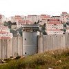 The Separation Wall in the Occupied Palestinian Territory and behind it an Israeli settlement.