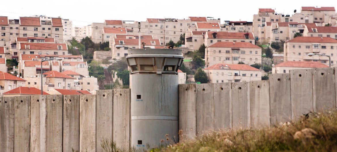 The Separation Wall in the Occupied Palestinian Territory and behind it an Israeli settlement.