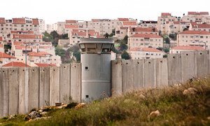 The Separation Wall in the Occupied Palestinian Territory and behind it an Israeli settlement.