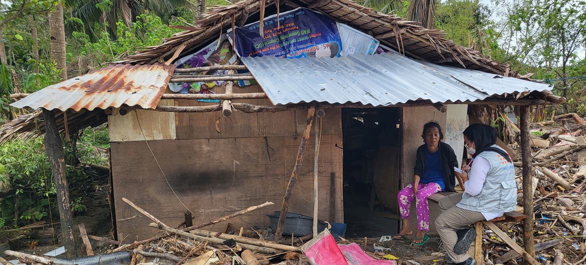 An expecting mother talks to a UNFPA staff member among the wreckage of her home after Typhoon Rai tore through the Philippines in in mid-December 2021.