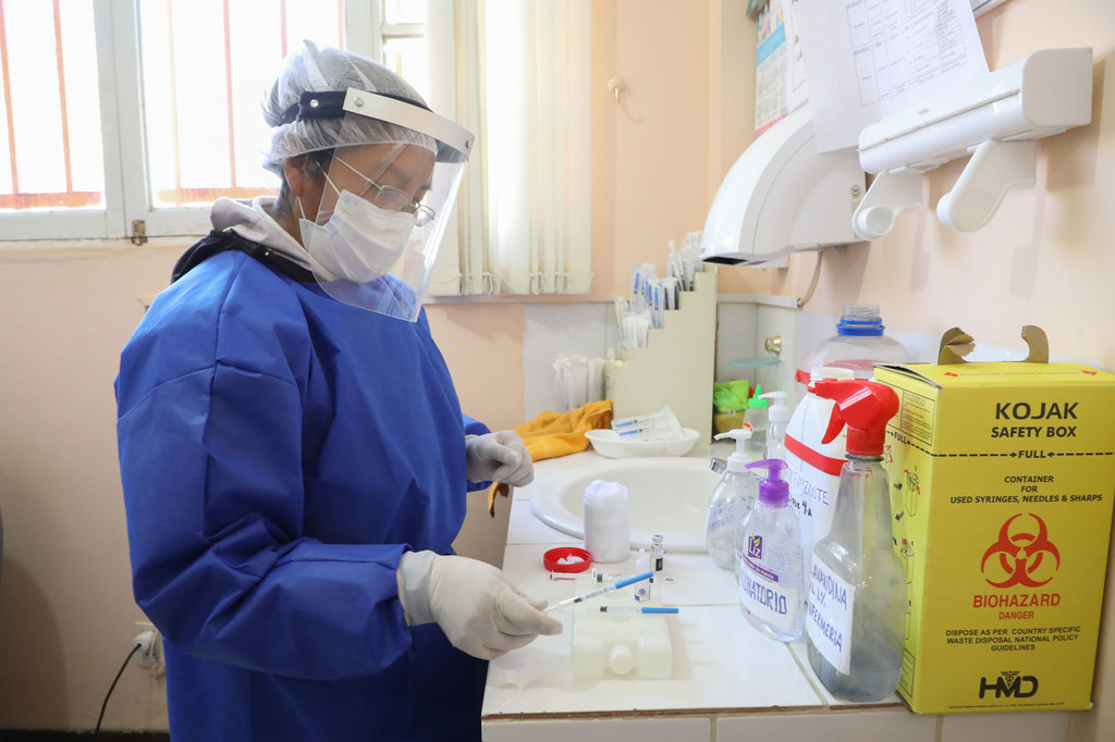 En una clínica médica de Bolivia se prepara un contenedor de objetos punzantes portátil para poder eliminar los residuos médicos cuando el personal médico visita a los pacientes en sus casas.
