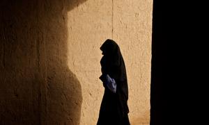 A woman walks through a corridor in a village in Zindajan district, Afghanistan.