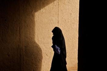 अफ़ग़ानिस्तान के ज़िन्दाजान ज़िले के एक गाँव में एक महिला, एक गलियारे से गुज़रते हुए.