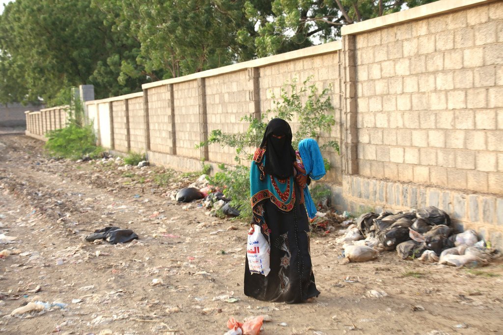 Une femme, portant son enfant qui souffre de malnutrition sévère et de problèmes de santé, se dirige vers un centre médical du gouvernorat d'Hodeida, au Yémen.