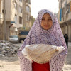 فتاة في حي الصالحين الفقير في حلب تحمل الخبز الذي يقوم بتوزيعه برنامج الأغذية العالمي