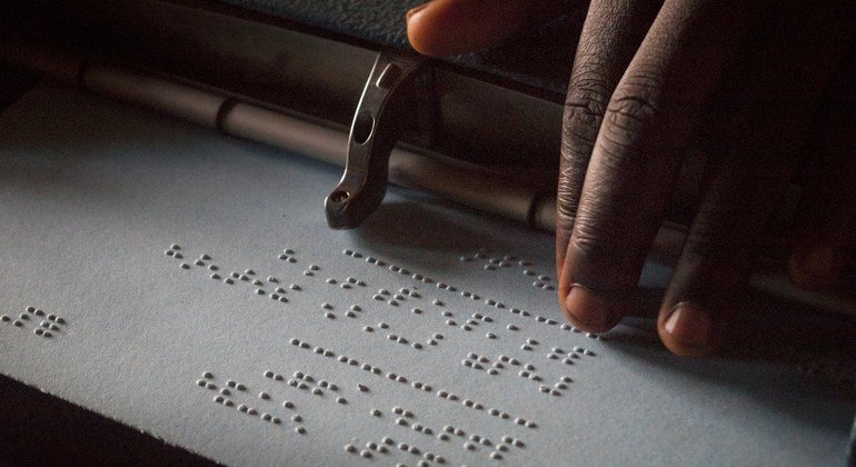 Uma criança lendo em braille em escola secundária no Uganda