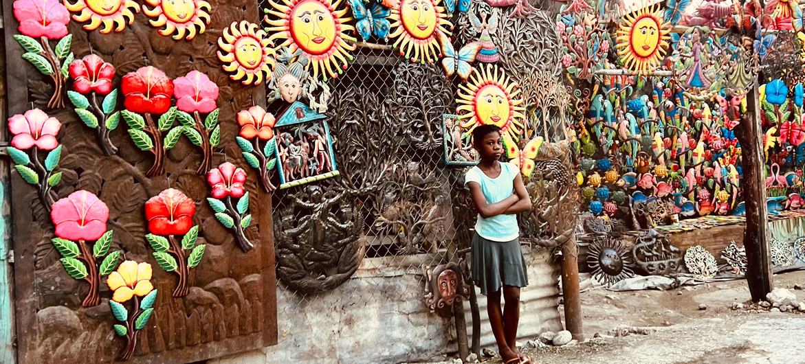 Una mujer joven muestra artículos de recuerdo a la venta en una pared en un barrio de Port-au-Prince.