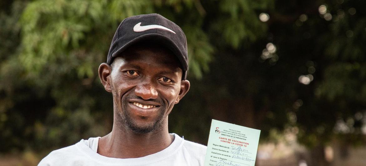 A man from Senegal holds a vaccination card from Covid-19.