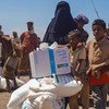 Une famille reçoit une aide alimentaire à un point de distribution de vivres à Ras al’Arah, dans le gouvernorat de Lahj, au Yémen.