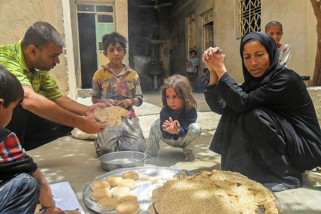 Una familia come pan hecho con un horno de leña y harina proporcionada por el PNUD en Siria.