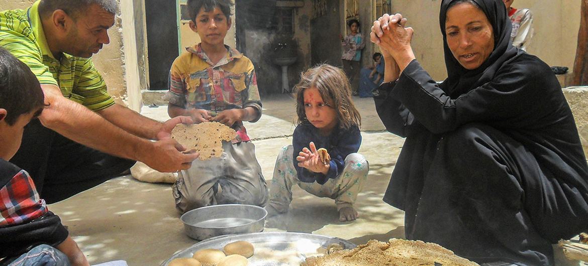 عائلة تأكل الخبز المصنوع على  فرن الحطب والطحين المقدم من برنامج الأمم المتحدة الإنمائي في سوريا.