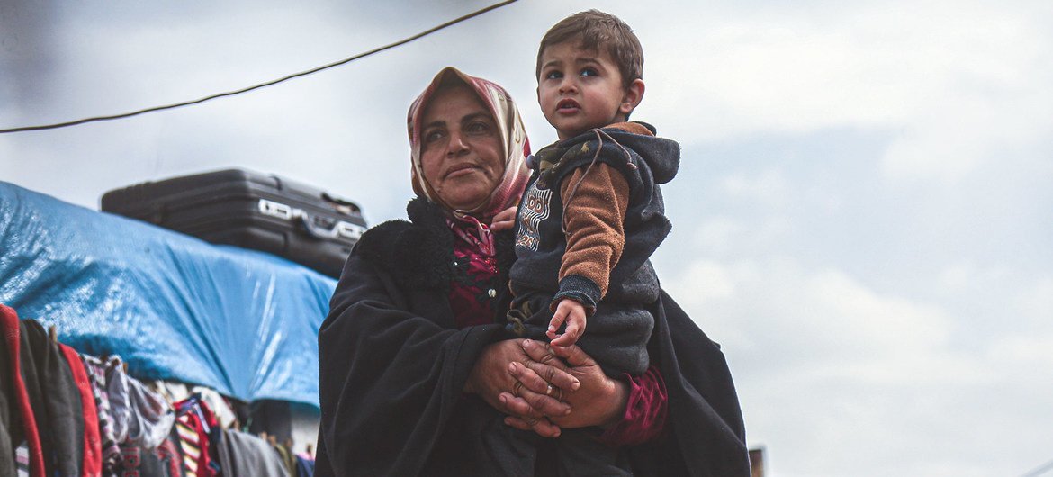 أرملة تحمل حفيدها في مخيم للنازحين شمال محافظة إدلب، سوريا.