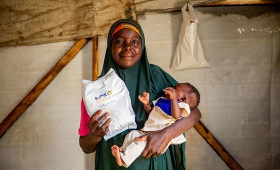 A mother and daughter receive food from the World Food Programme at a camp for displaced people in Maiduguri, Nigeria.