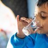 Un jeune garçon boit un verre d'eau provenant d'un nouveau réseau d'eau relié au camp de réfugiés de Za'atari en Jordanie.
