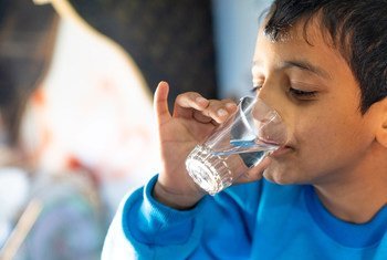 Un jeune garçon boit un verre d'eau provenant d'un nouveau réseau d'eau relié au camp de réfugiés de Za'atari en Jordanie.
