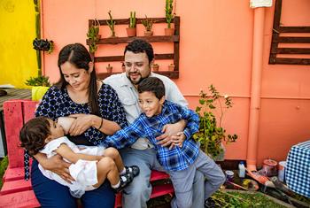 A mother breastfeeds her daughter in Guatemala City while her husband attends to their son.