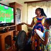 أم تساعد ابنتها البالغة من العمر ثماني سنوات على أخذ دروس على التلفزيون أثناء جائحة كوفيد في المنزل في مان، كوت ديفوار.