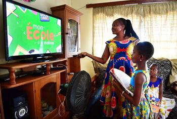 A mother helps her eight-year-old daughter to take classes on television during the COVID-19 pandemic at home in Man, Côte d'Ivoire.