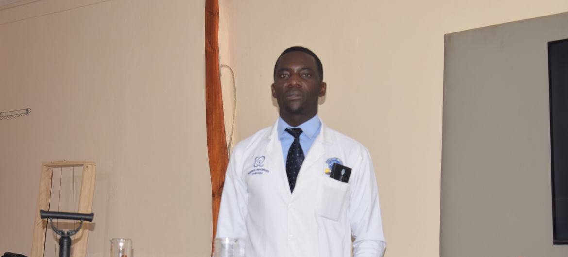 Wilson Kamunye, mwanzilishi wa Moving Laboratory, anasimama nyuma ya meza iliyojaa vifaa vya maonyesho ya sayansi na vifaa vya maabara.