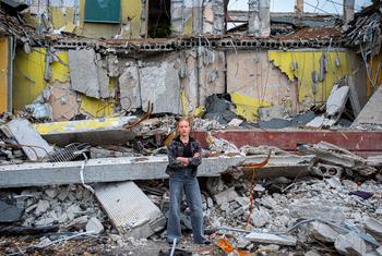 A twelve-year-old girl stands in front of her school in Kharkiv, Ukraine. It was destroyed in an air strike and she will now study online.