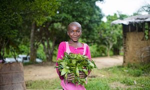 A child holds vegetables grown in her garden in a village in Cameroon.